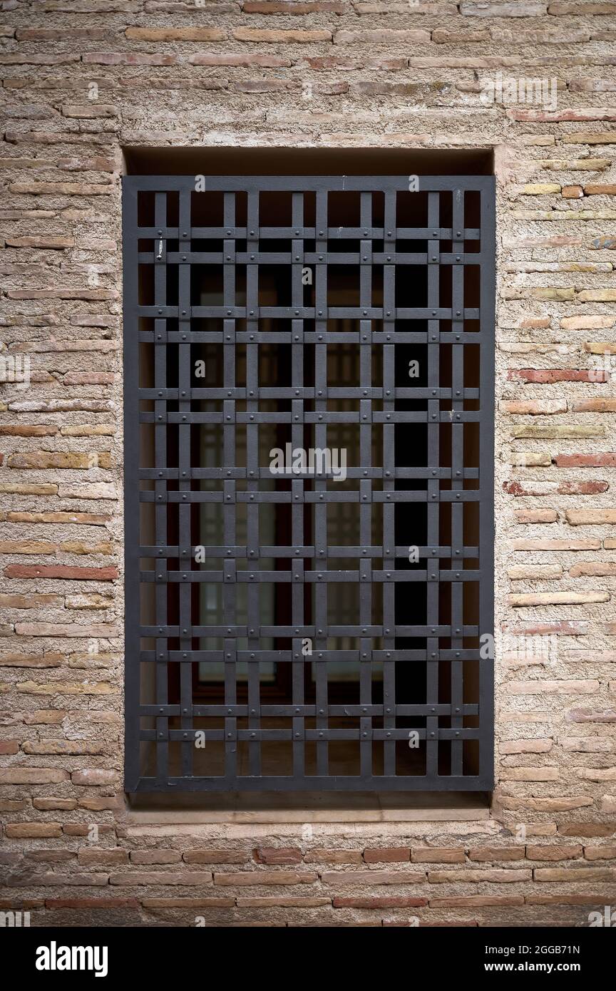 Detail eines alten Gitters auf einem Fenster in einer alten Ziegelmauer Stockfoto