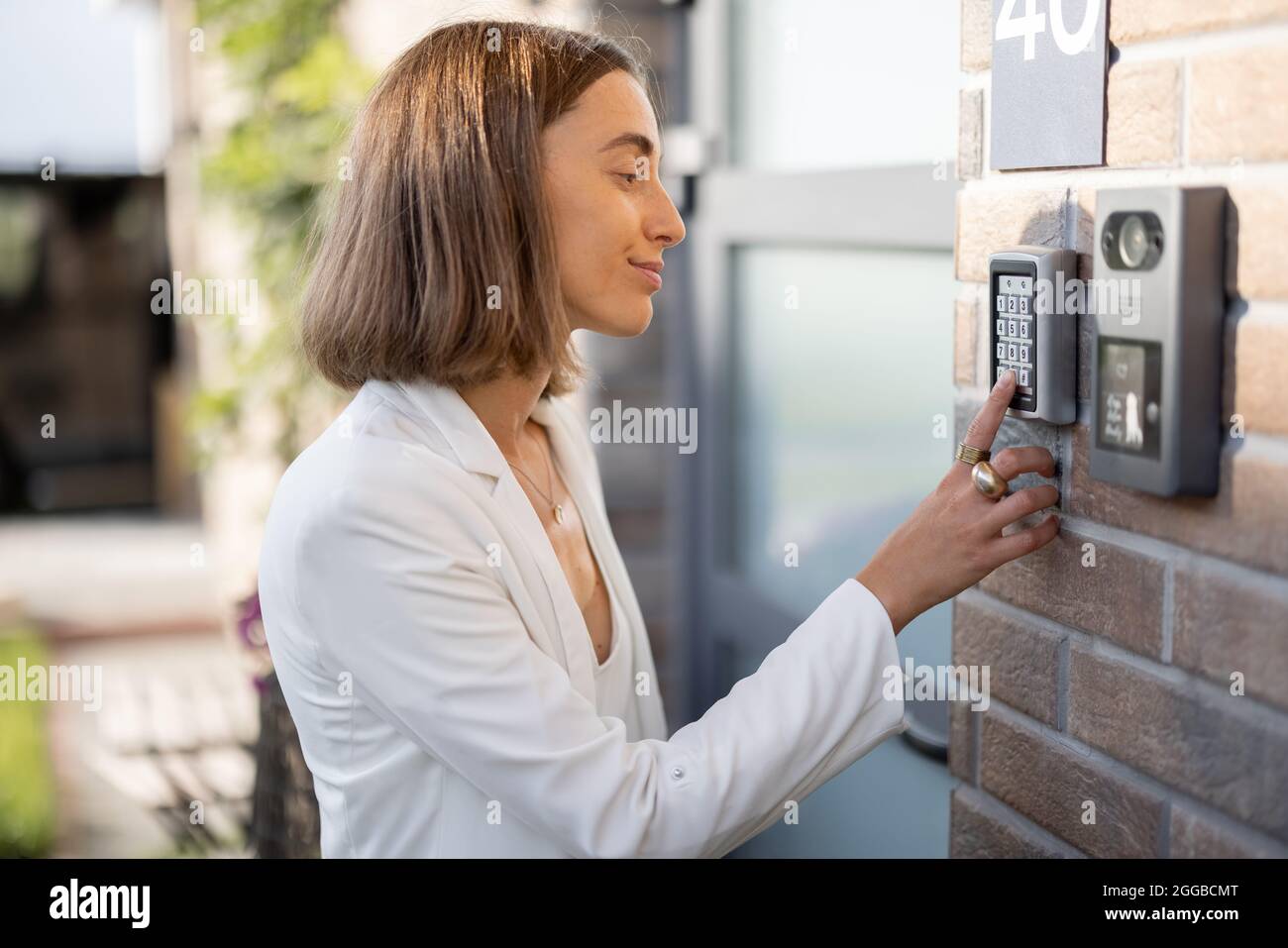 Frau, die Code über eine Tastatur eingibt, um auf eine Tür zuzugreifen Stockfoto