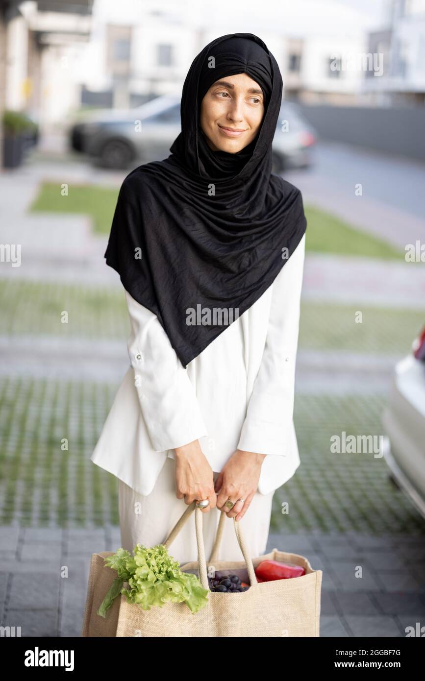 Muslimische Frau mit Lebensmitteln in der Nähe des Hauses Stockfoto
