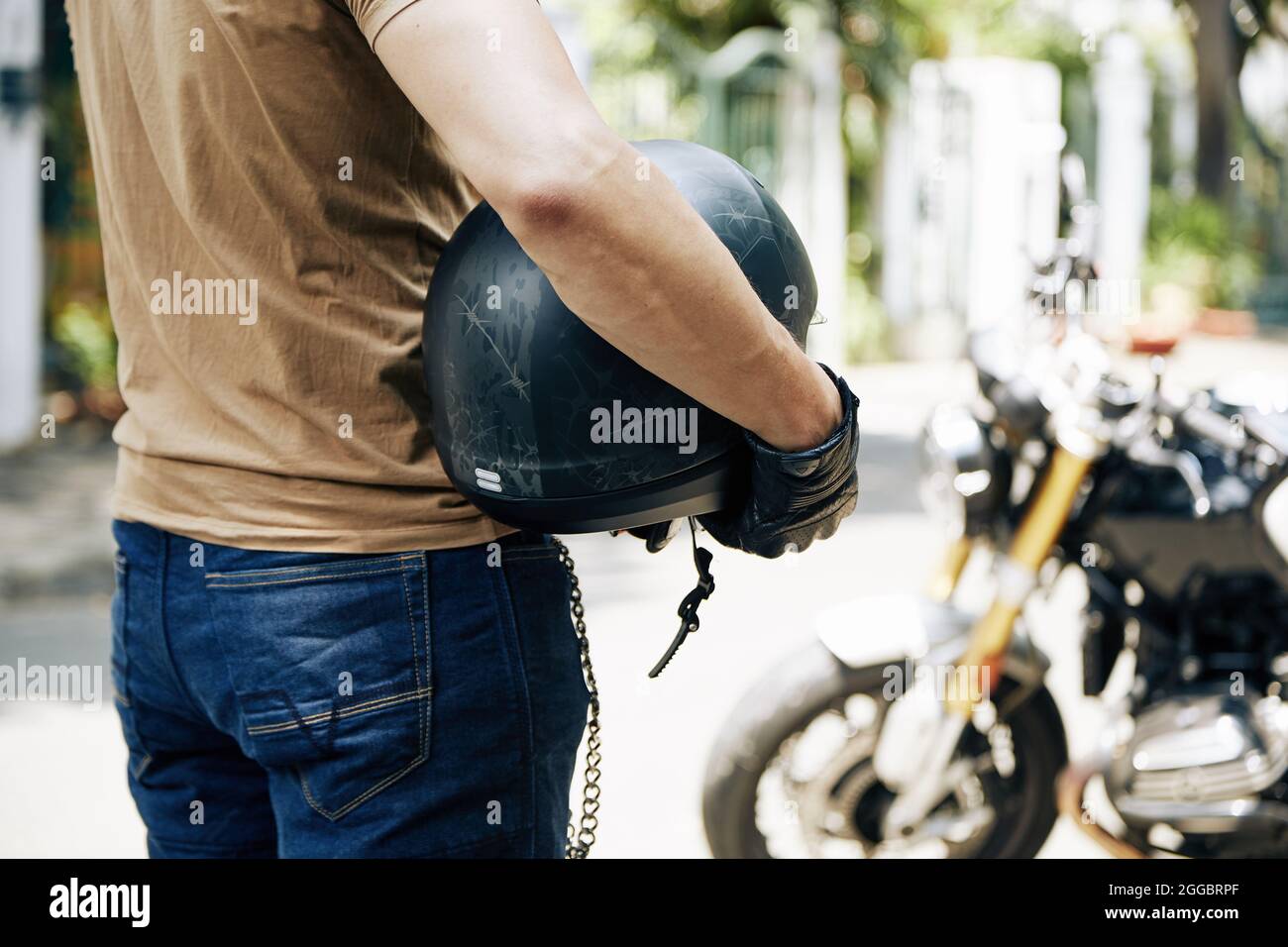 Mann mit Helm in den Händen, der sein Motorrad anschaut, selektiver Fokus Stockfoto