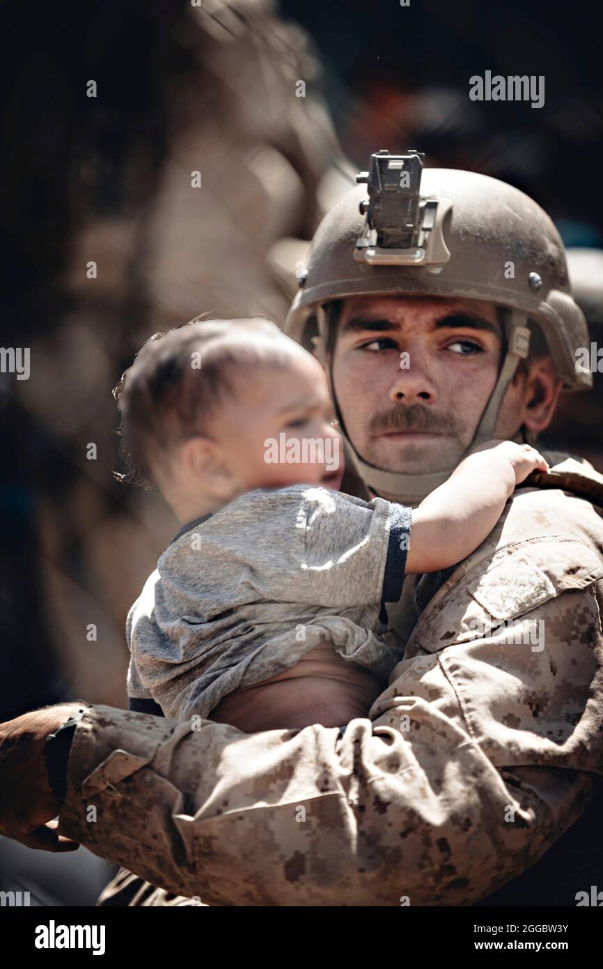 Kabul, Afghanistan. August 2021. Eine US-Marine mit dem Special Purpose Marine Air-Ground Task Force Crisis Response Team, Assiste und afghanisches Kind im Evakuierungskontrollzentrum am Hamid Karzai International Airport während der Operation Allies Refuge am 26. August 2021 in Kabul, Afghanistan. Quelle: Planetpix/Alamy Live News Stockfoto