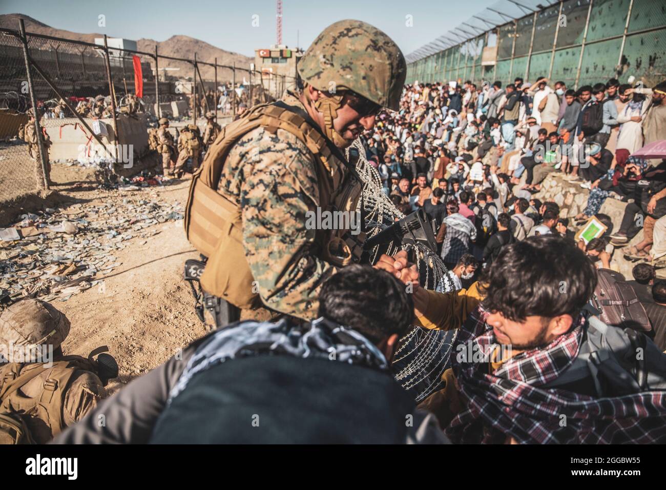 Kabul, Afghanistan. August 2021. Eine US-Marine mit dem Krisenreaktionsteam der Special Purpose Marine Air-Ground Task Force unterstützt afghanische Flüchtlinge im Evakuierungskontrollzentrum am Hamid Karzai International Airport während der Operation Allies Refuge am 26. August 2021 in Kabul, Afghanistan. Quelle: Planetpix/Alamy Live News Stockfoto