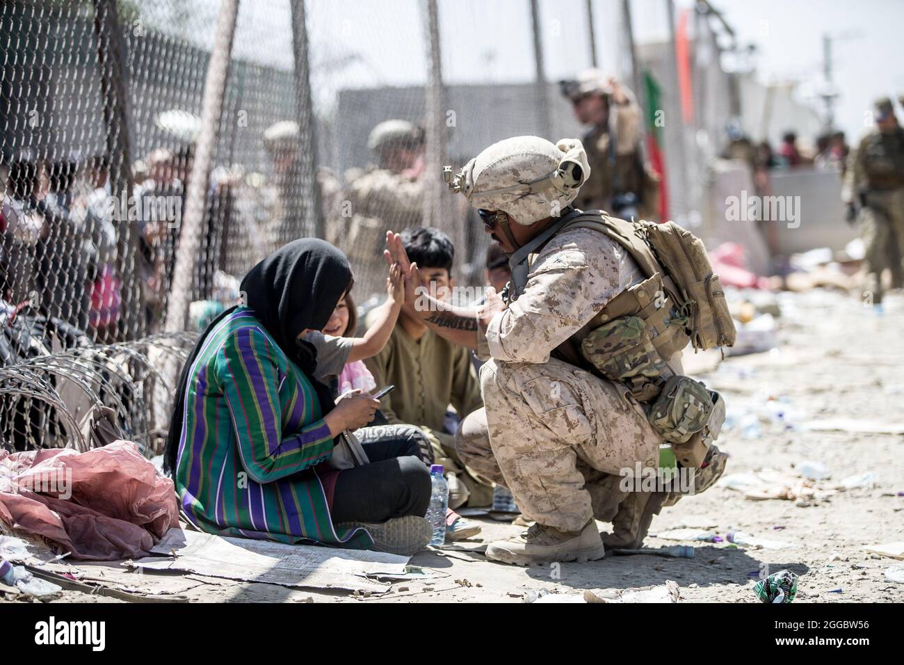 Kabul, Afghanistan. August 2021. Eine US-Marine mit dem Special Purpose Marine Air-Ground Task Force Crisis Response Team, hat während der Operation Allies Refuge am 26. August 2021 in Kabul, Afghanistan, ein afghanisches Kind im Evakuierungskontrollzentrum am Hamid Karzai International Airport hochgejuckt. Quelle: Planetpix/Alamy Live News Stockfoto