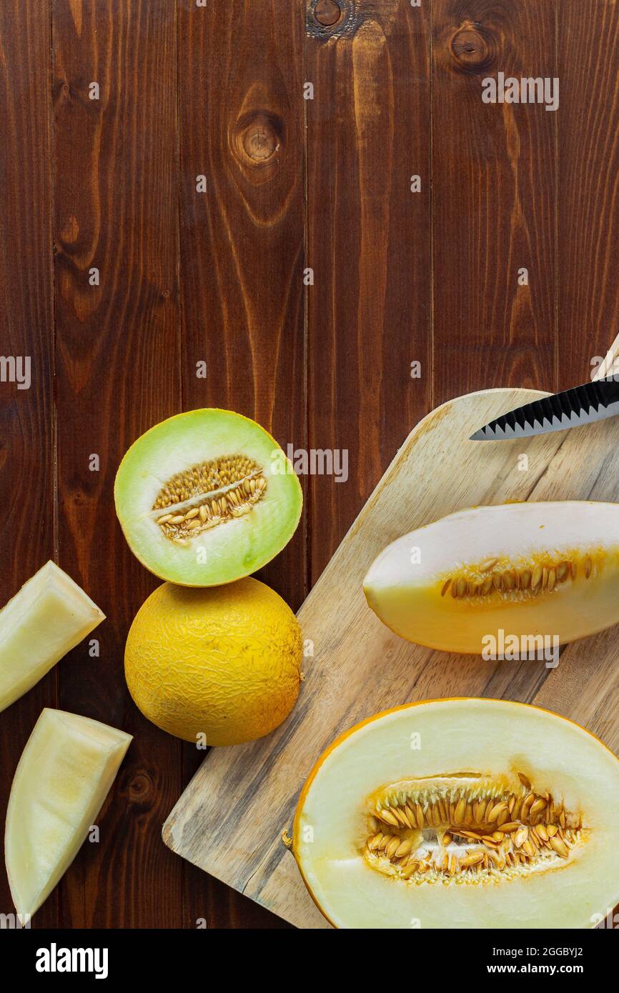 Draufsicht auf Scheiben Honigmelone auf Holzschneidebrett und rustikales Holz mit Kopierraum Stockfoto