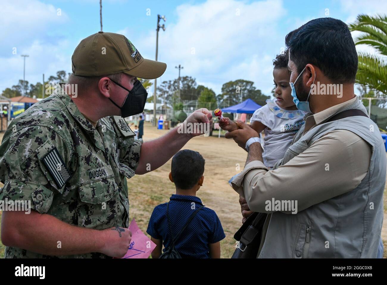 Rota, Spanien. August 2021. Ein Seemann der US-Marine spielt mit einem afghanischen Kind, das von Kabul zur Naval Air Station Rota am 29. August 2021 in Rota, Spanien, evakuiert wurde. NAS Rota stellt im Rahmen der Operation Allies Refuge eine vorübergehende Unterkunft für Evakuierte aus Afghanistan bereit. Quelle: Planetpix/Alamy Live News Stockfoto