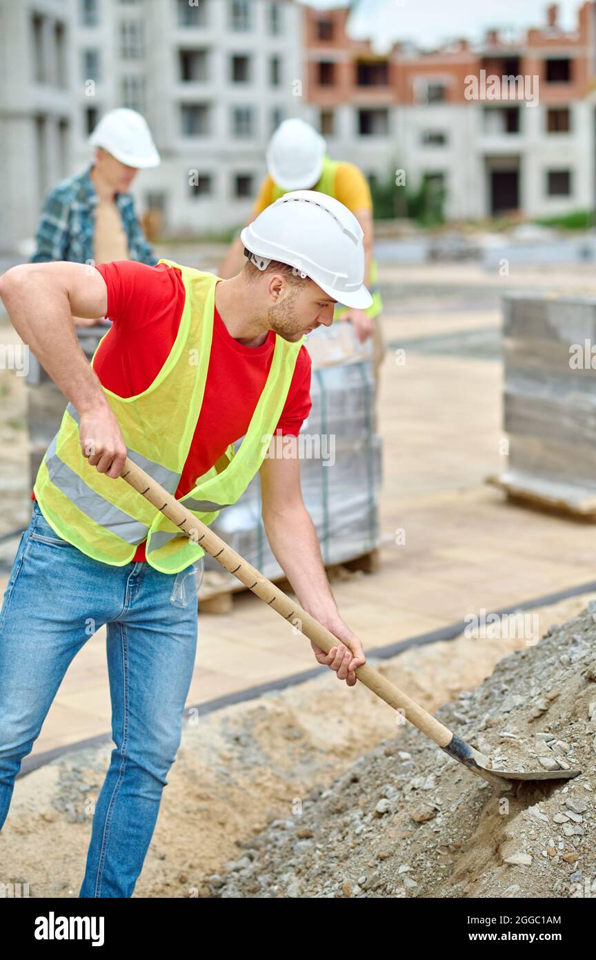 Fleißiger männlicher Arbeiter, der mit einem Spaten den Boden gräbt Stockfoto