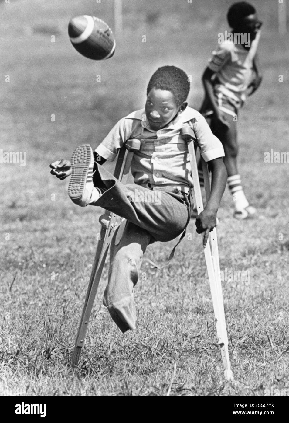 Austin Texas USA, 1984: Der schwarze Schüler Patrick Skeaton, der sein rechtes Bein aufgrund einer Spina bifida verlor, benutzt Holzkrücken, um an der Wooten Elementary School in Austin, Texas, zu kommen, während er in den regulären Unterricht integriert wird. Später wurde er mit einer Beinprothese ausgestattet. Teil einer erweiterten Fotofunktion. ©Bob Daemmrich Stockfoto