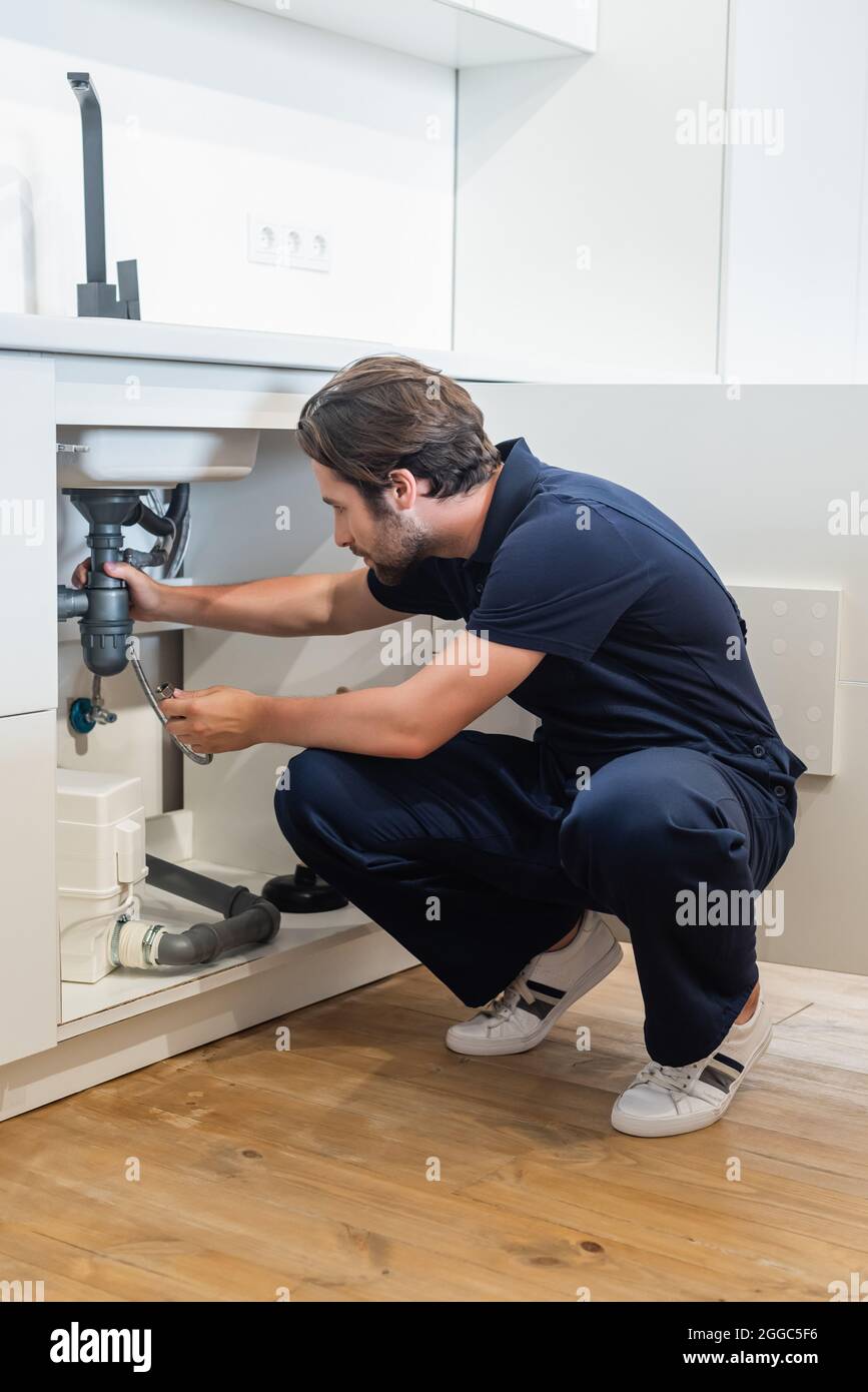 Klempner in einheitlicher Befestigung Metallschlauch unter Küchenspüle Stockfoto