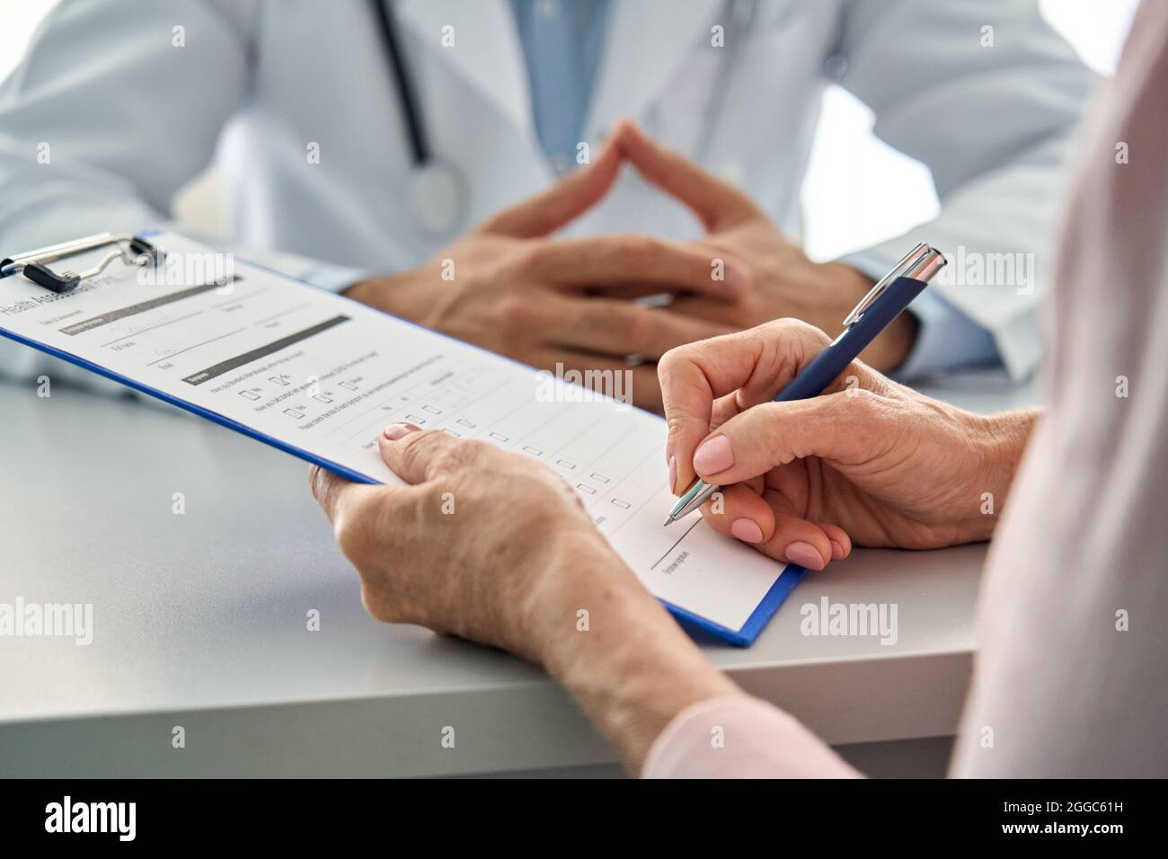 Nahaufnahme älterer Patient, der das Formular für medizinische Gesundheitsdaten in der Klinik ausfüllt. Stockfoto