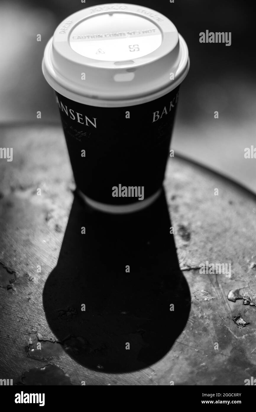 LONDON, VEREINIGTES KÖNIGREICH - 16. Aug 2017: Eine vertikale Aufnahme eines Take Away Cup und dessen Schatten auf dem Tisch Stockfoto