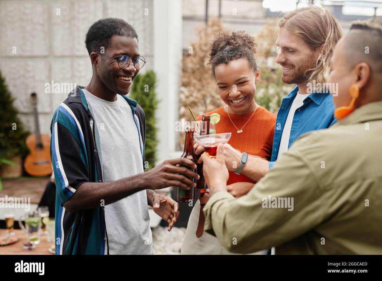 Waist up Schuss von unbeschwerten jungen Menschen klirren Getränke während draußen Party mit Freunden genießen Stockfoto