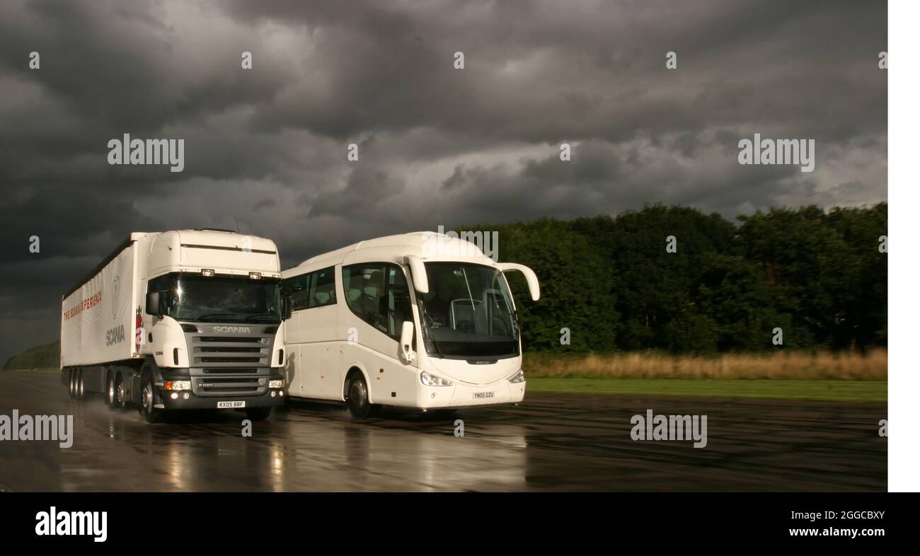 LKW-LKW passiert einen Bus auf einer nassen Teststrecke Stockfoto