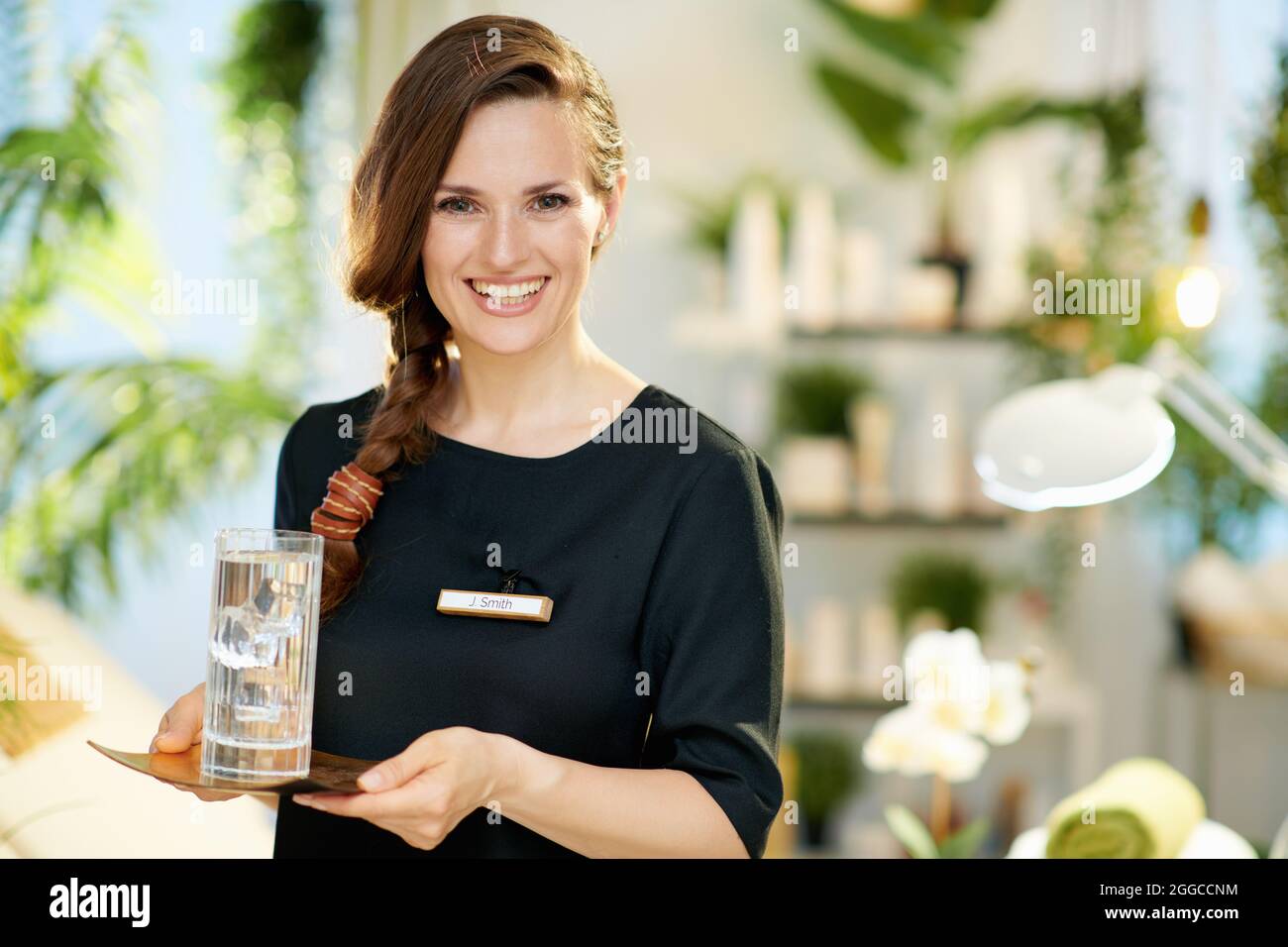 Lachelnde Angestellte Mit Einer Tasse Wasser Im Modernen Beauty Studio Stockfotografie Alamy