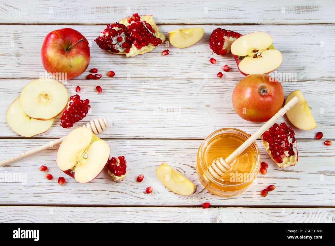 Happy Rosh Hashanah. Traditionelle Symbole der jüdischen Neujahrsfeier. Äpfel, Granatäpfel und Honig auf weißem Holzhintergrund. Platz für yo Stockfoto