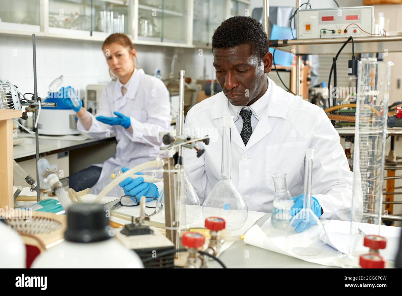 Männliche Labortechniker mit verschiedenen Glasröhren, Mädchen auf dem Hintergrund Stockfoto