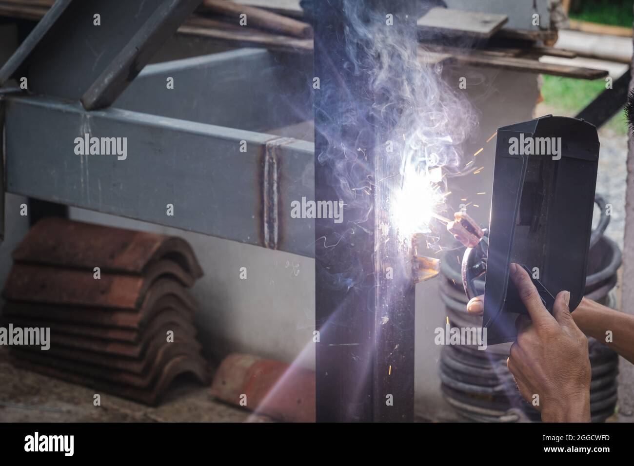 Mann Schweißer, der eine Metalltreppenkonstruktion in einem Wohngebäude mit einer Schweißmaschine macht. Stockfoto