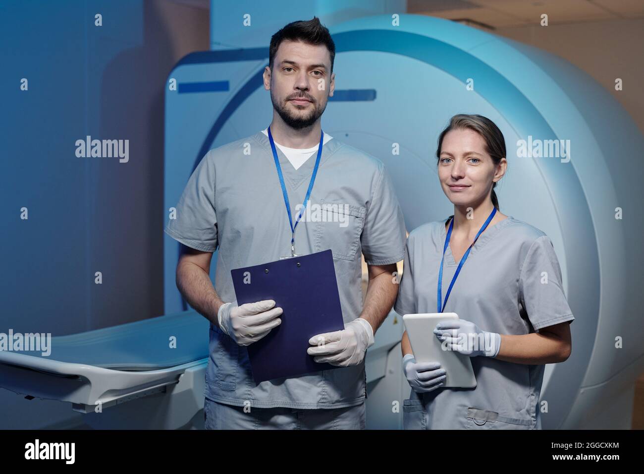 Zwei junge, selbstbewusste Kliniker in Uniform und Handschuhen im CT-Labor Stockfoto