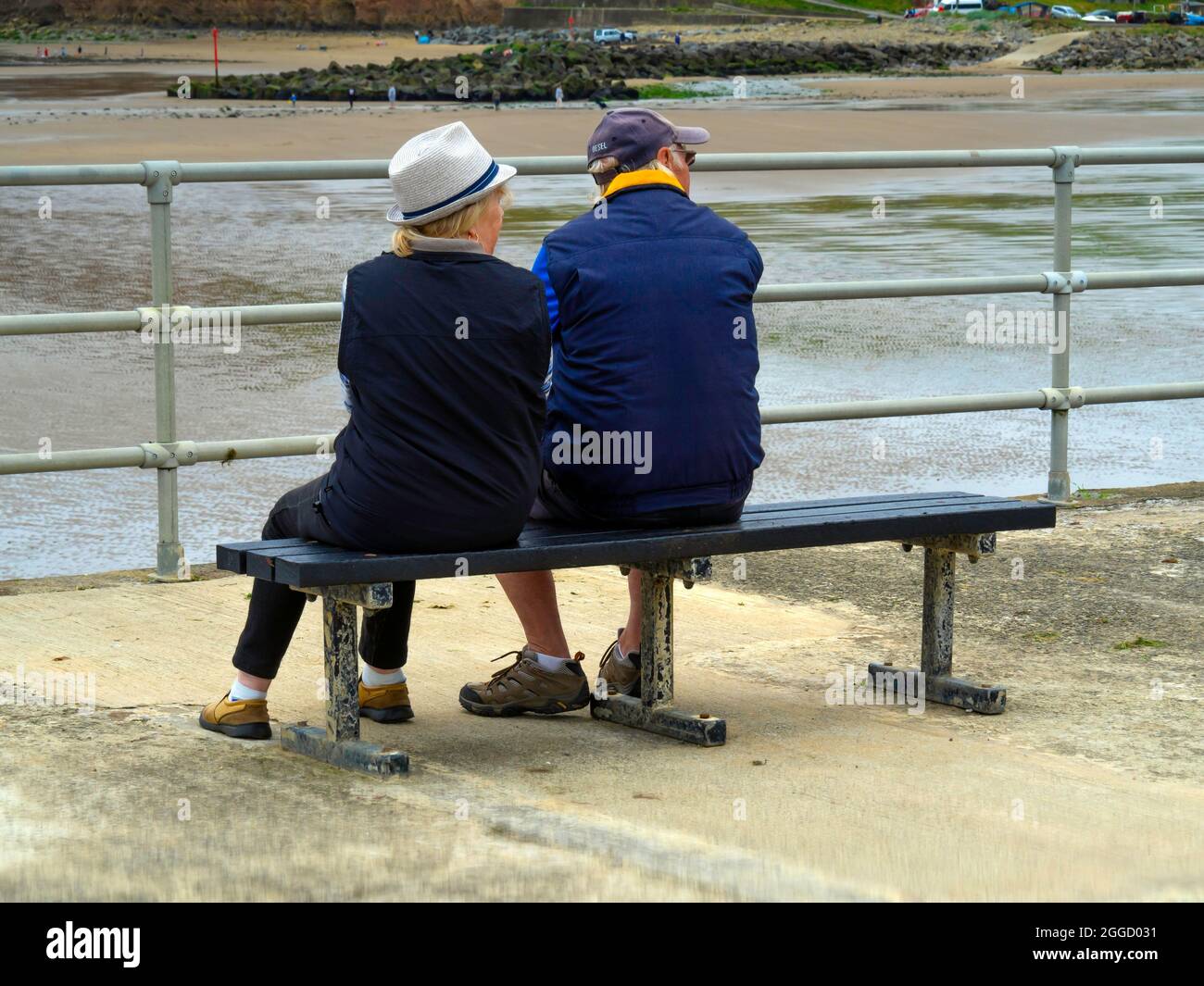 Mann und Frau genießen eine Pause auf einer Bank mit Blick auf das Meer bei Skinningrove Stockfoto