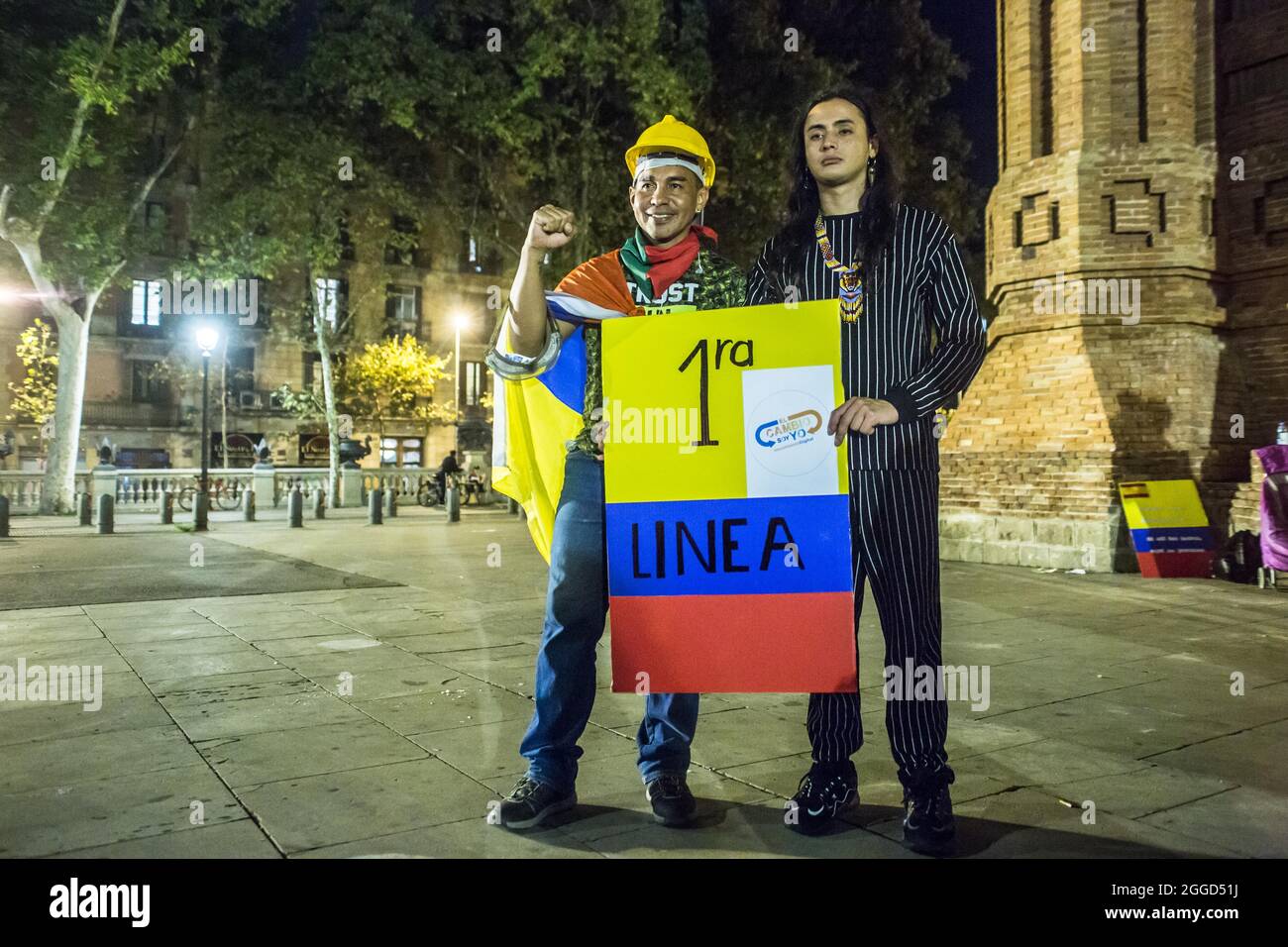 Barcelona, Spanien. August 2021. Erste Verteidigungslinie bei den regierungsfeindlichen Protesten in Kolumbien wird Ricardo 'Profe' mit einem Protestanten mit einem Banner mit den Farben Kolumbiens gesehen, das sagt: „erste Zeile, die Veränderung bin ich“. Rund 200 Menschen haben vor dem Arc de Triomf in Barcelona gegen die 6402 außergerichtlichen Tötungen demonstriert, die von der Armee im Zusammenhang mit dem bewaffneten Konflikt in Kolumbien begangen wurden, ein Phänomen, das als „falsche positive“ bekannt ist. Bild: DAX Images/Alamy Live News Stockfoto