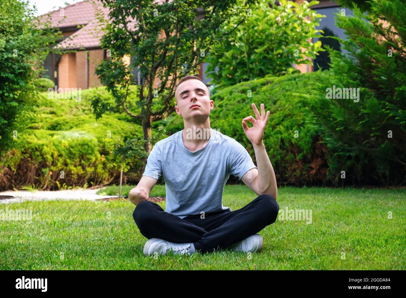 Junger Mann mit Behinderung meditiert im Freien Yoga Stockfoto