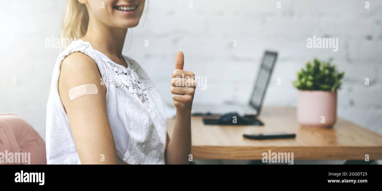 Geimpfte Frau mit Gips auf der Schulter und Daumen in ihrem Arbeitsbüro. Verantwortungsvolles Handeln und Impfkonzept. Platz kopieren Stockfoto