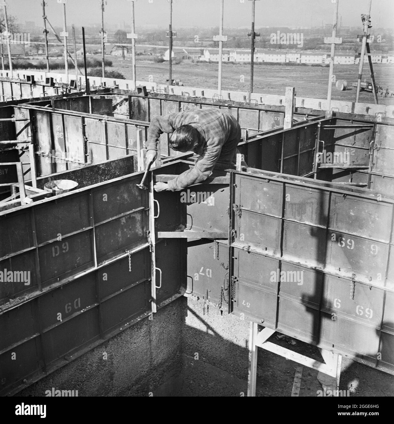 Ein Mann, der die Schalung für den Bau von Easiform-Wohnungen in Bristol, möglicherweise auf dem Patchway Estate, festsetzt. „Easiform“ war eine Methode der in situ vorgegossenen Betonkonstruktion, die John Laing und Son Ltd ab 1919 entwickelten. Stockfoto