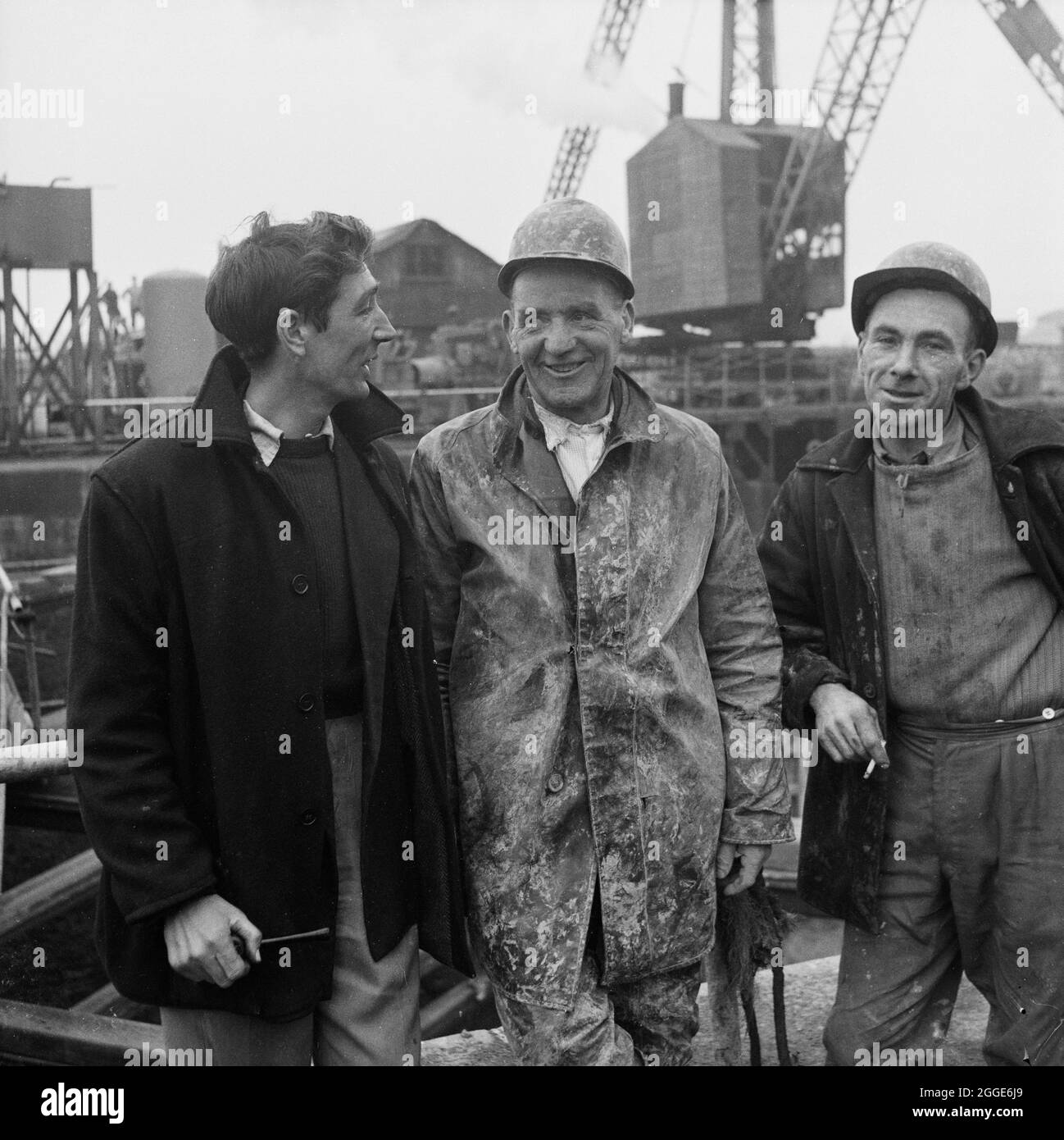 Ein Gruppenportrait von drei Banden, S. Jones, T. Cummersky und M. Ryan, die am Portishead Dock-Projekt beschäftigt sind. Eine ausgeschnittene Version dieses Bildes wurde im Abschnitt „Menschen“ der Mai 1959-Ausgabe des monatlichen Laing-Newsletters „Team Spirit“ veröffentlicht. Im Jahr 1958 begannen die Sanierungsarbeiten an der Schleuseneinfahrt zum Portishead Dock für die Port of Bristol Authority. Der Eingang der Schleuse war durch eine Abschur- und Wellenbewegung beschädigt worden und musste entfernt und erneuert werden, und die vorhandenen Wände wurden untermauert. Gleichzeitig wurden die Arbeiten am letzten Drittel des Kraftwerks Portishead „B“ aufgenommen. Stockfoto