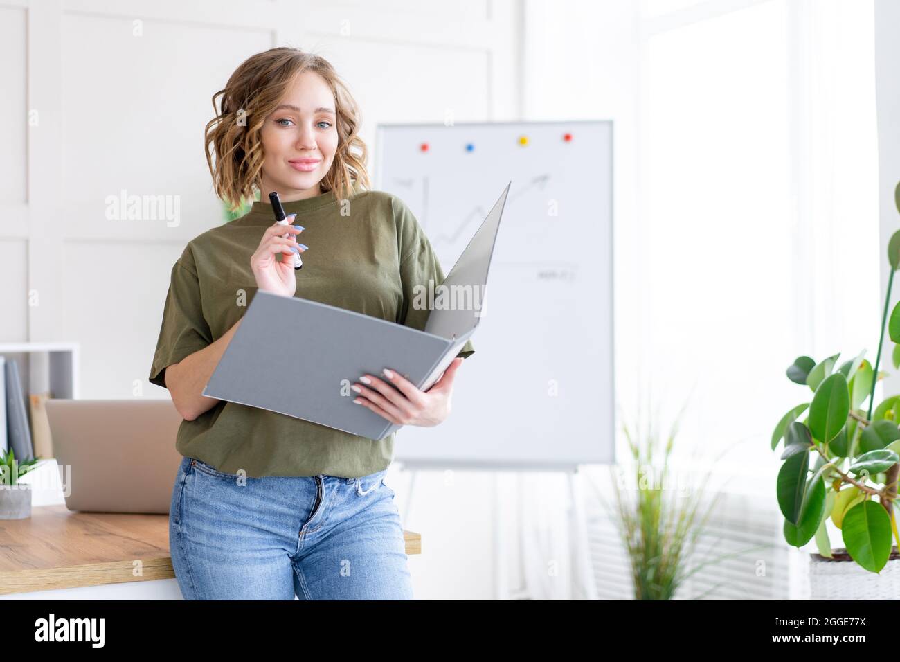 Geschäftsfrau hält Ordner für Papier schreiben Marker denken träumen neben Bürotisch stehen. Business Person femal ypoung Erwachsenen kaukasisch auf Modus Stockfoto