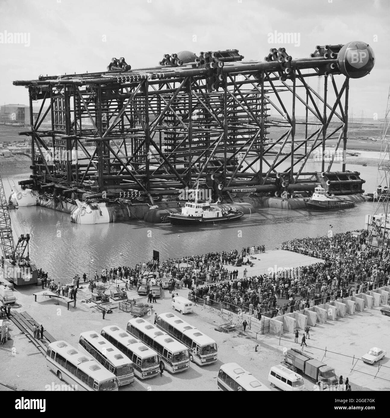 Eine Vogelperspektive auf die Ölplattform Greythorp II und eine große Menschenmenge versammelten sich zur Namenszeremonie in Greythorp. In den frühen 1970er Jahren bauten Laing Pipelines Offshore die Graythorp-Fabrikationswerft und das Trockendock auf dem Gelände der alten William Gray Shipyard. Das Unternehmen schuf ein Trockendock, das für den Bau von Bohrgeräten mit fester Plattform in der Nordsee für das Nordseeölprojekt BP verwendet wurde. Die Ölplattform Greythorp I wurde am Samstag, dem 29. Juni 1974, gestartet und am Wochenende vom 14.-15. Juni 1975 wurde Greythorp II benannt und schwebte aus dem Hafenbecken den Seaton hinunter Stockfoto