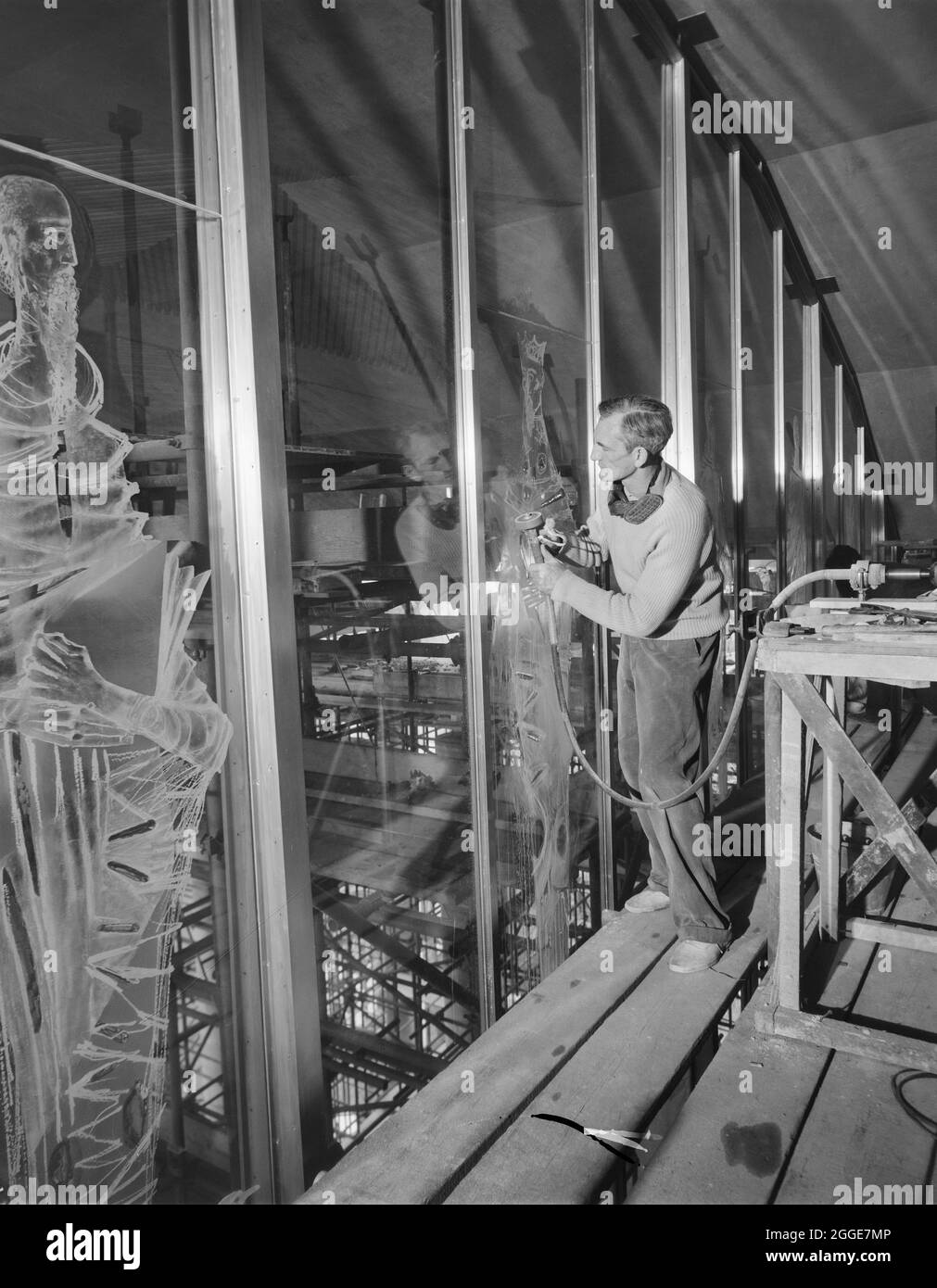 John Hutton graviert eine Glasscheibe auf der Westleinwand der Coventry Cathedral. Die westliche Leinwand ist vom Glasgraveur John Hutton (1906-1978) mit Figuren von Heiligen und Engeln graviert. Die Herstellung des Bildschirms dauerte über 10 Jahre und auf den Glaspaneelen sind 66 Figuren eingraviert. Stockfoto