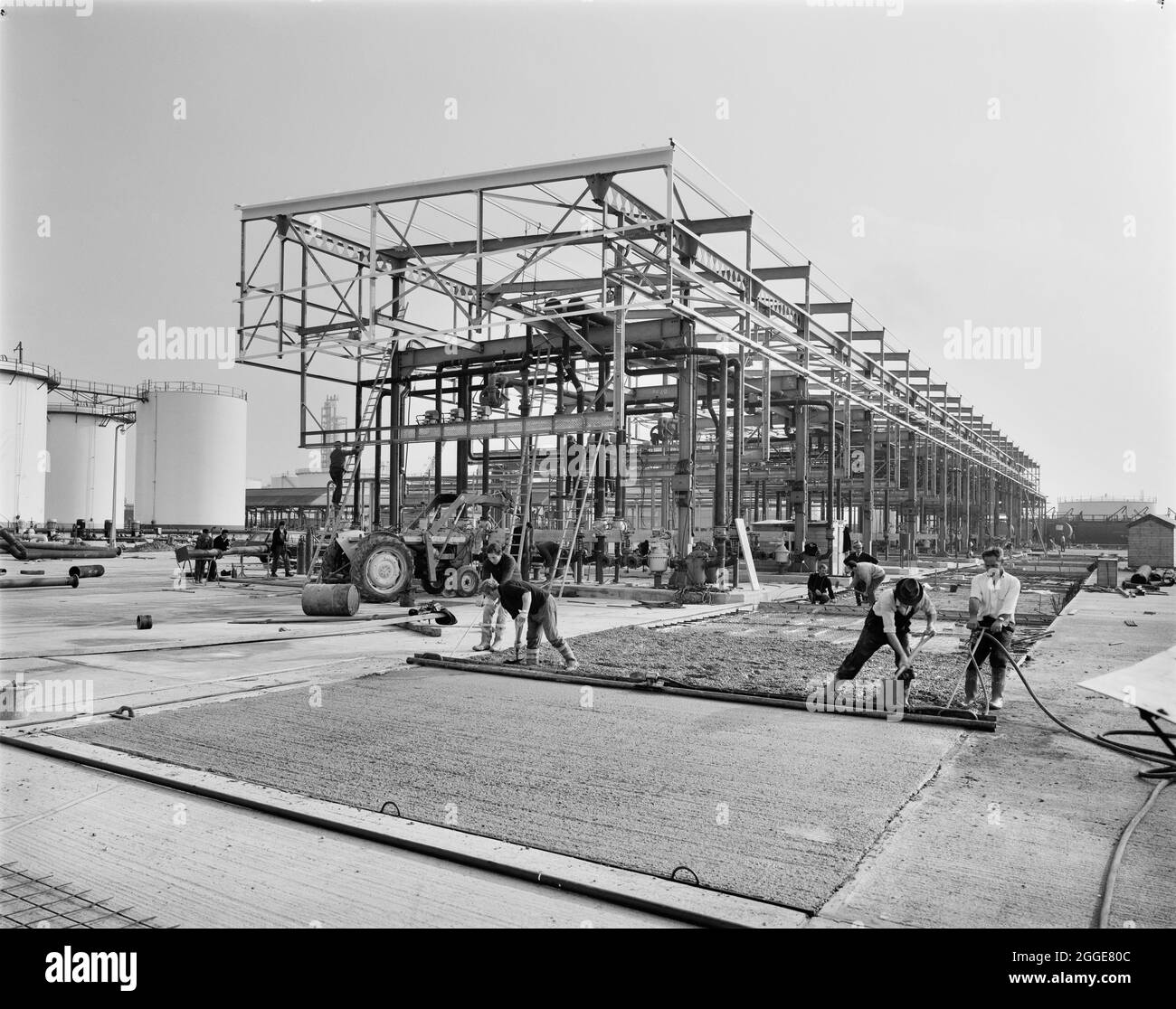 Arbeiter, die eine Fläche vor Straßenladerinseln im Coryton Mobil Bulk Terminal pflastern. Dieses Bild wurde als Teil des Breaking New Ground Project in Zusammenarbeit mit dem John Laing Charitable Trust in den Jahren 2019-20 katalogisiert. Stockfoto