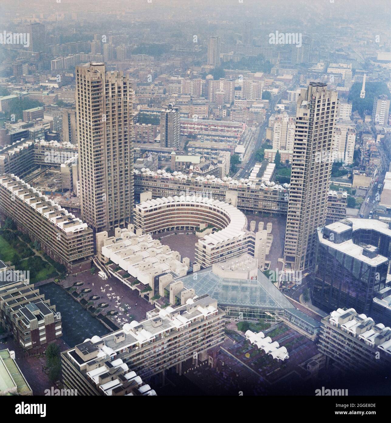 Ein Blick auf die fertiggestellte Barbican-Entwicklung von einem hohen Aussichtspunkt nach Südosten, der den Shakespeare Tower (links) und den Cromwell Tower (rechts) auf beiden Seiten des Frobisher Crescent zeigt. #begannen die Arbeiten am Bau der Barbican-Entwicklung von London & 1962 x2019. Der Bau dieser komplexen Megastruktur sollte in sechs Phasen erfolgen, wobei verschiedene Bauunternehmer auf dem Gelände arbeiten. 1964 gewannen John Laing und Son Ltd die Ausschreibung für Phase III Laing war auch für den Bau des Barbican Arts Center, Phase V, verantwortlich, das in den frühen 1970er Jahren begann und 19 fertiggestellt wurde Stockfoto