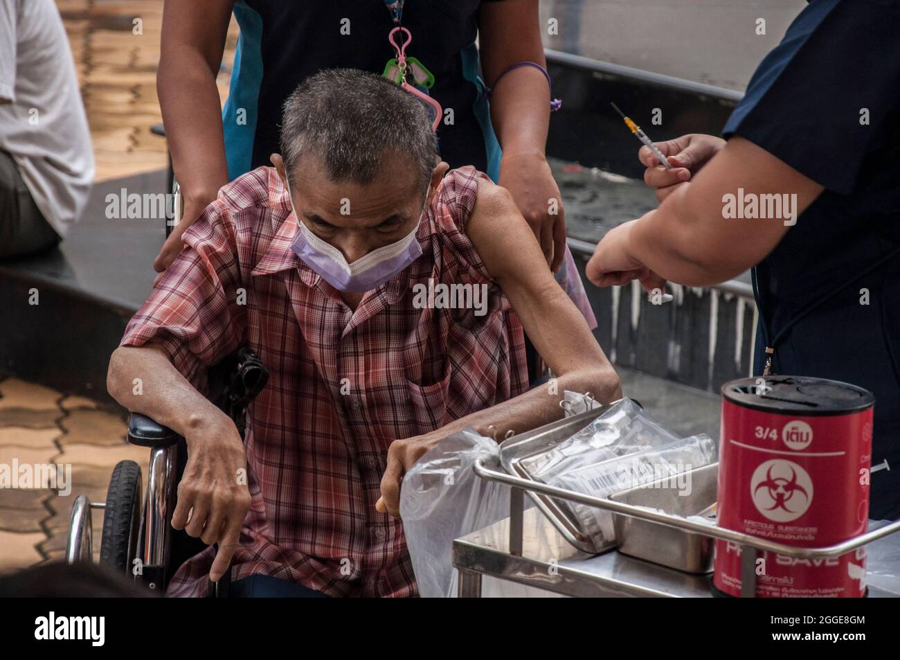 Ein Gesundheitsmitarbeiter verabreicht einem älteren Mann an der Raj Pracha High School in Samut Prakarn den Impfstoff Pfizer-BioNTech Covid-19. Das Bang Chak Hospital in der Provinz Samut Prakarn wurde für die Walk-in-Impfung der Einwohner von Samut Prakarn eröffnet, um ihre erste Dosis des Pfizer-Impfstoffs in Raj Pracha High zu erhalten. Einwohner der Provinz Samut Prakarn mit hohem Risiko, die sich für den Impfstoff qualifiziert haben, sind über 60 Jahre alt, schwanger oder haben bereits bestehende Erkrankungen, erhielten vom 30. August bis 1. September 2021 die erste Dosis des Pfizer-BioNTech COVID-19-Impfstoffs, die um 8:00 Uhr begann und um 14:00 Uhr endete Stockfoto