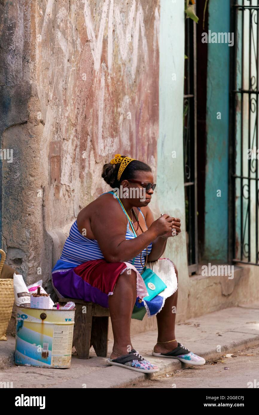 Die dicke, dunkelhäutige Kubanerin, Kubanerin, die vor der Eingangstür auf einem Hocker sitzt, die Altstadt, die Hauptstadt Havanna, die Provinz Havanna, die Großantillen Stockfoto