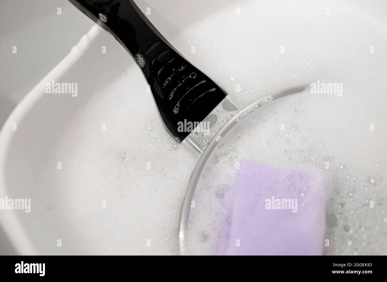 Bratpfanne in Seifenlauge, Spülwasser in weißer Kunststoffschüssel Stockfoto