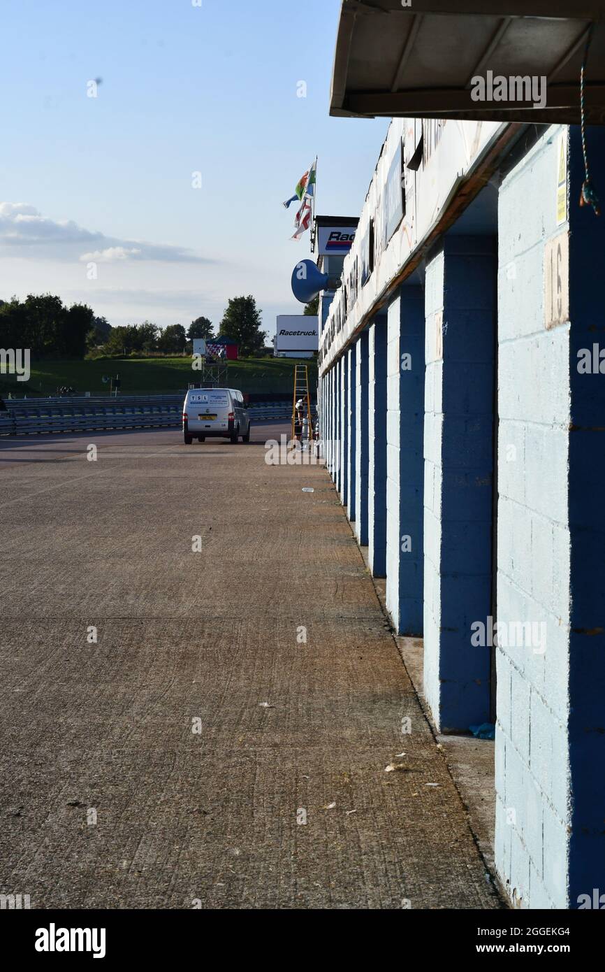 Eine Reihe von Betonblockgaragen mit Fahnen, die in der Ferne fliegen, und einem Mann auf einer Leiter mit seinem Van. Stockfoto