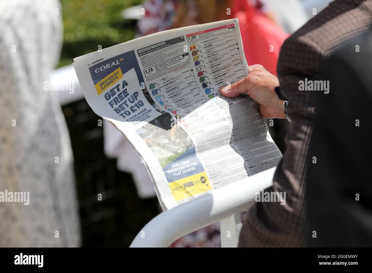 Fans von Pferderennen haben sich beim Lesen der Zeitung „Racing Post“ an einem Renntag auf der Goodwood Race Course in West Sussex, Großbritannien, ein Bild gemacht. Stockfoto