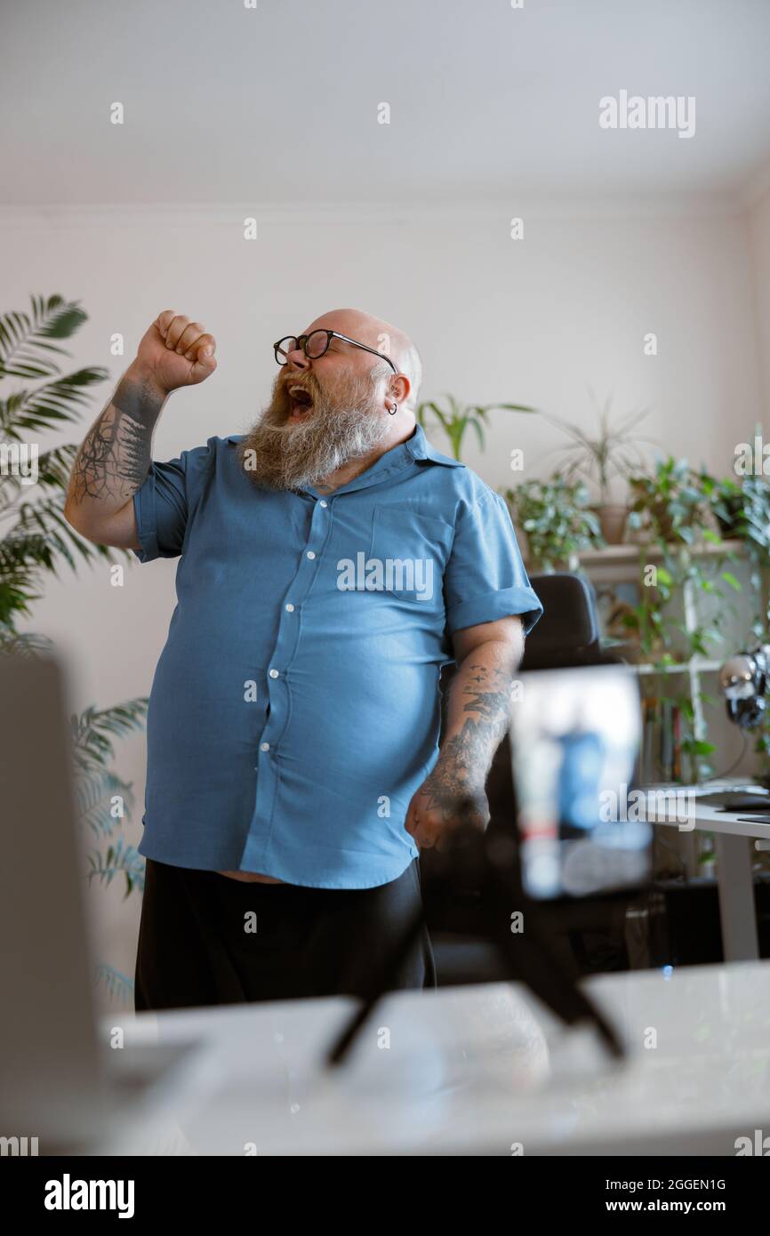 Ausdrucksstarker Mann mit Übergewicht singt Song, der neues Video für den Blog zu Hause aufnimmt Stockfoto