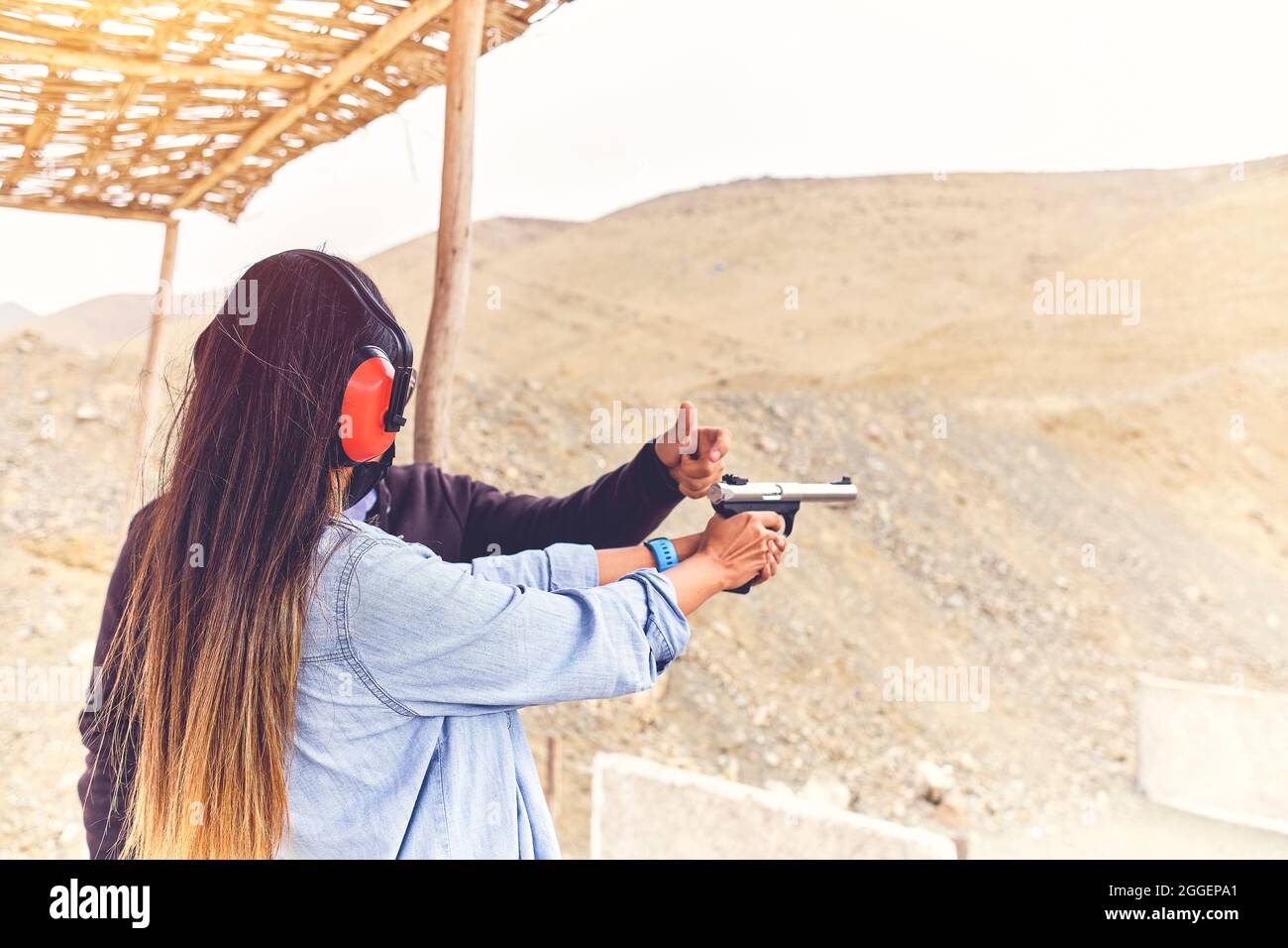 Frau löst Stress, Instruktor hilft Frau mit Waffe Stockfoto