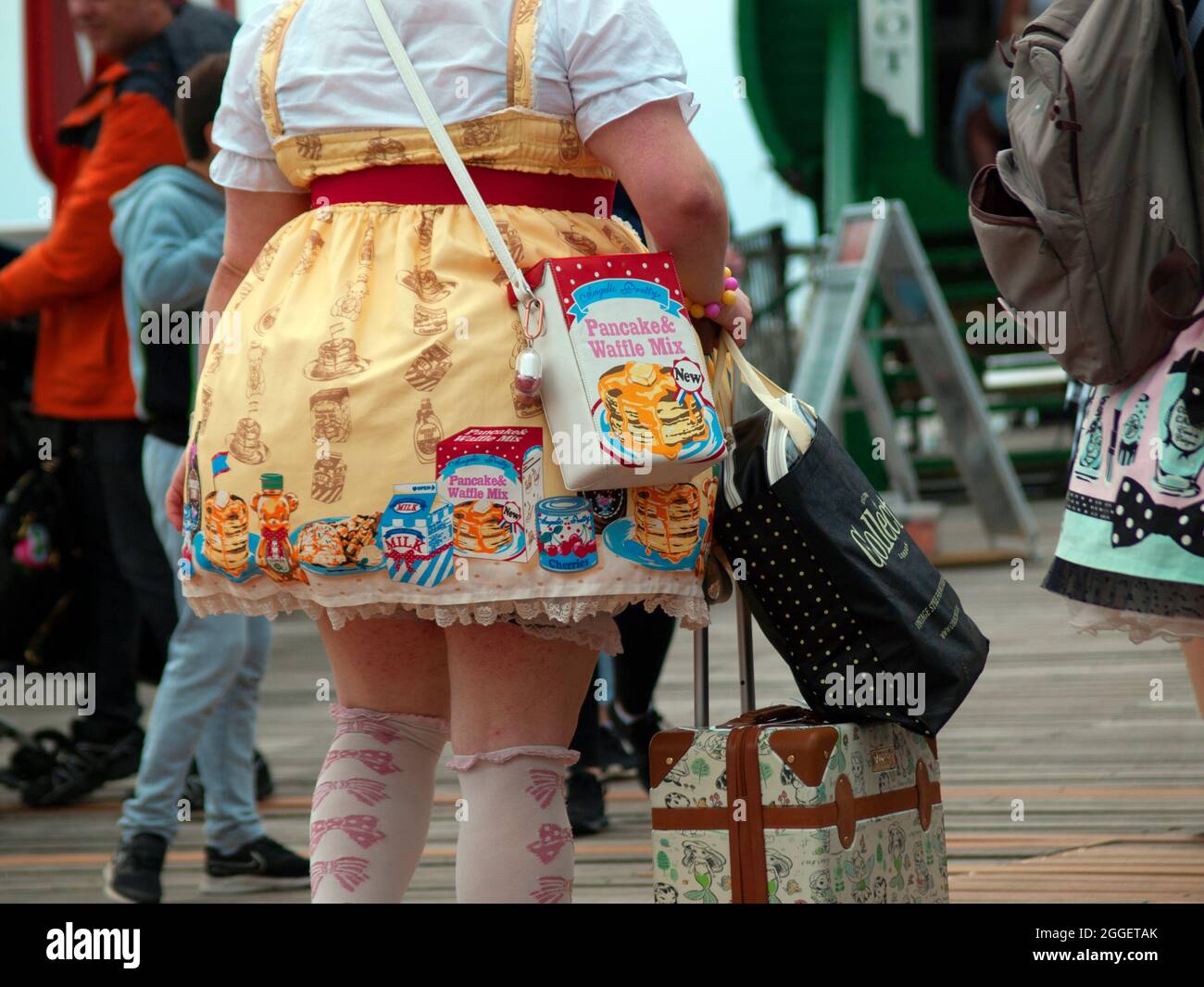 Ein Mädchen in einem Kleid mit Lebensmittelverpackung in einer Straße in Brighton Stockfoto