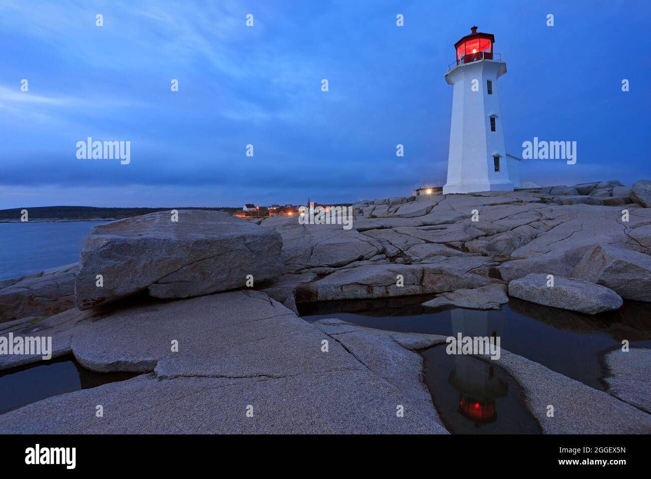 Peggy’s Cove Lighthouse, beleuchtet in der Abenddämmerung mit Reflexion im Wasser, Nova Scotia, Kanada Stockfoto
