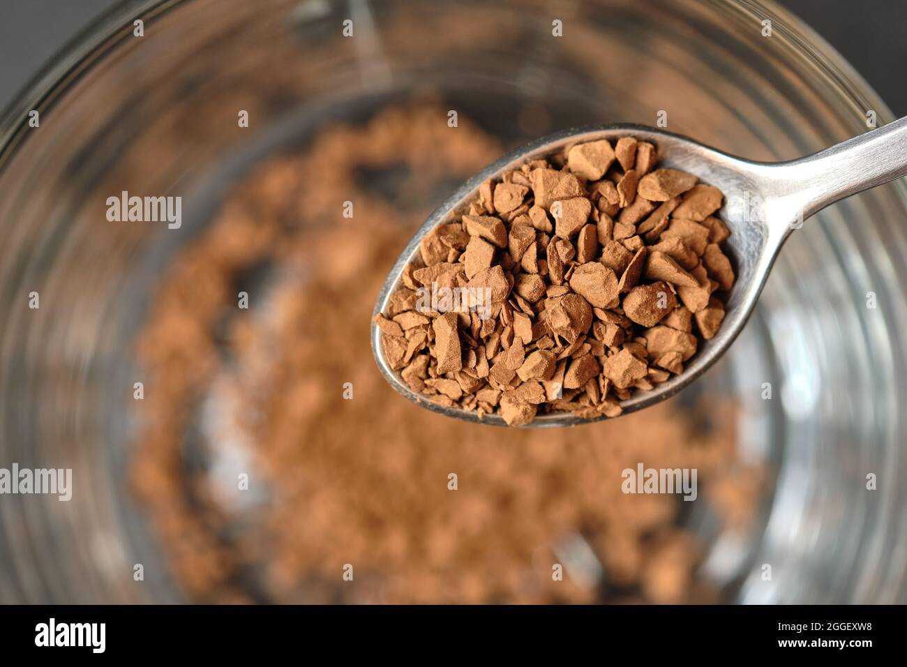 Gefriergetrockneter Instant-Kaffee auf Teelöffel mit Glas-Kaffeetasse Hintergrund. Stockfoto