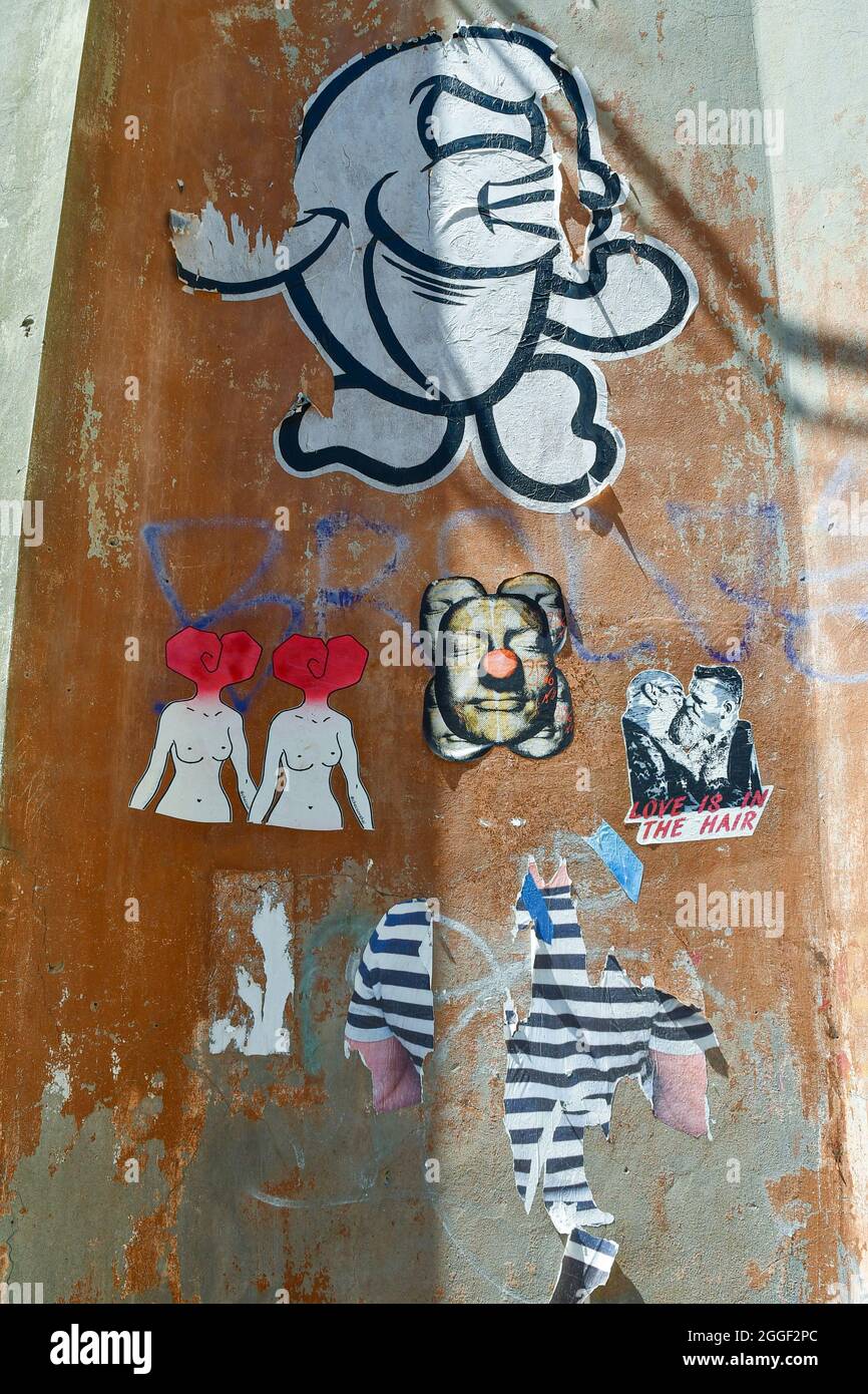 Detail einer Wand mit verschiedenen Paste-up-Kunstwerken, eine Art Straßenkunst, mit einem 'Fisch' von Merioone, Livorno, Toskana, Italien Stockfoto