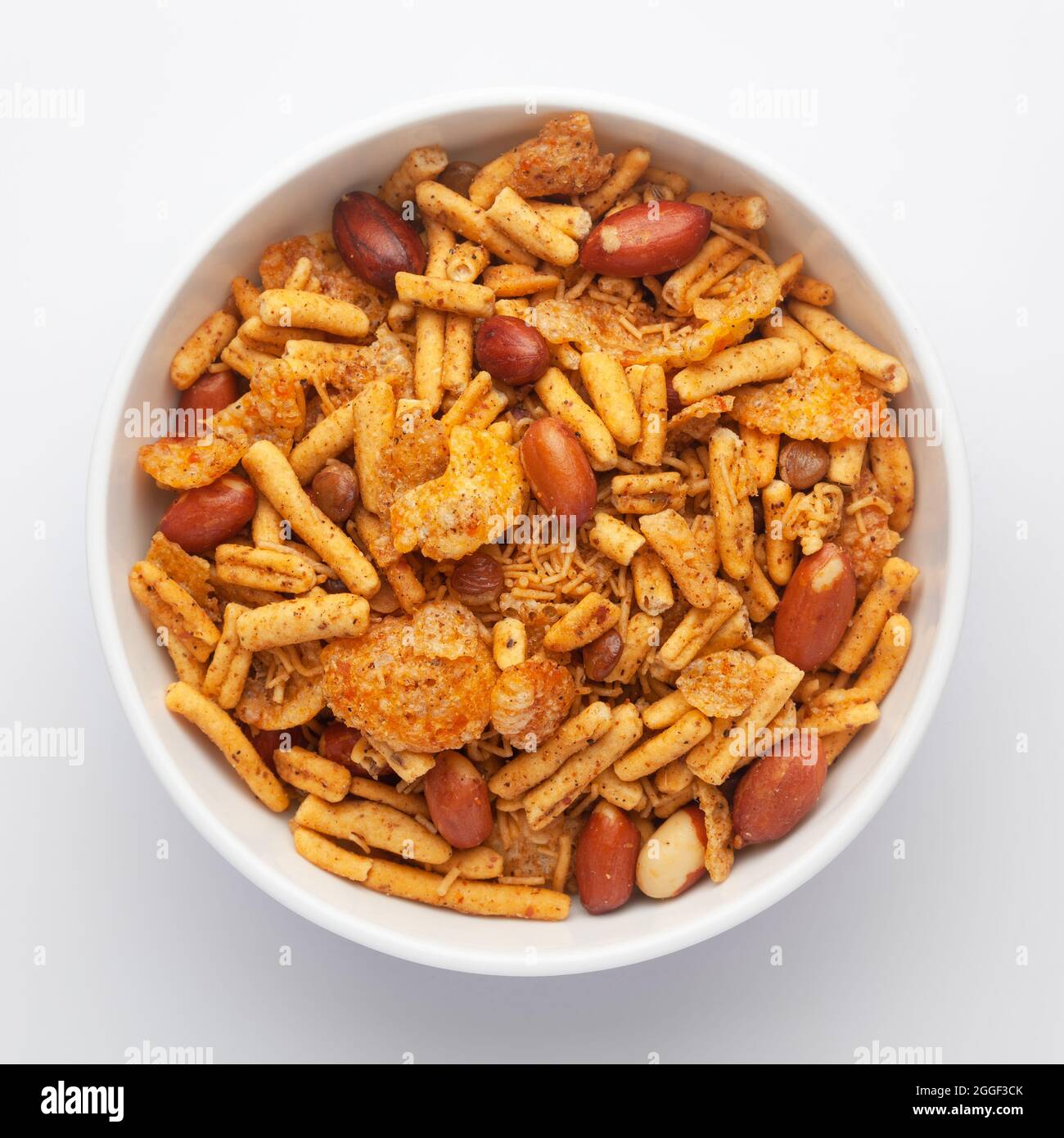 Nahaufnahme einer würzigen Chatpata-Mischung in einer weißen Keramikschale aus Erdnüssen und Cornflakes. Indische, würzige Snacks (Namkeen), Blick von oben Stockfoto