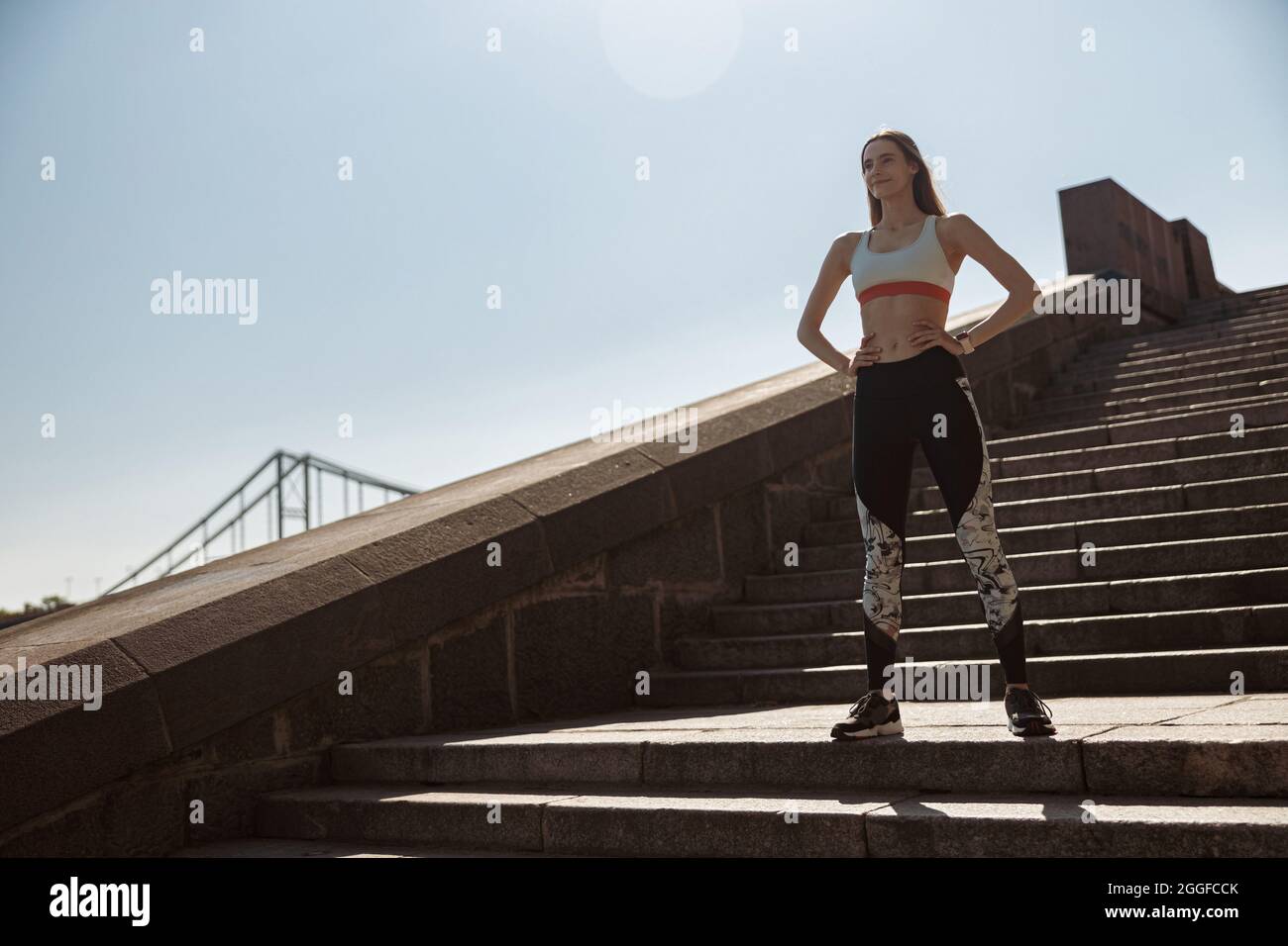 Frau im Trainingsanzug steht auf Steintreppen am Stadtdamm Stockfoto