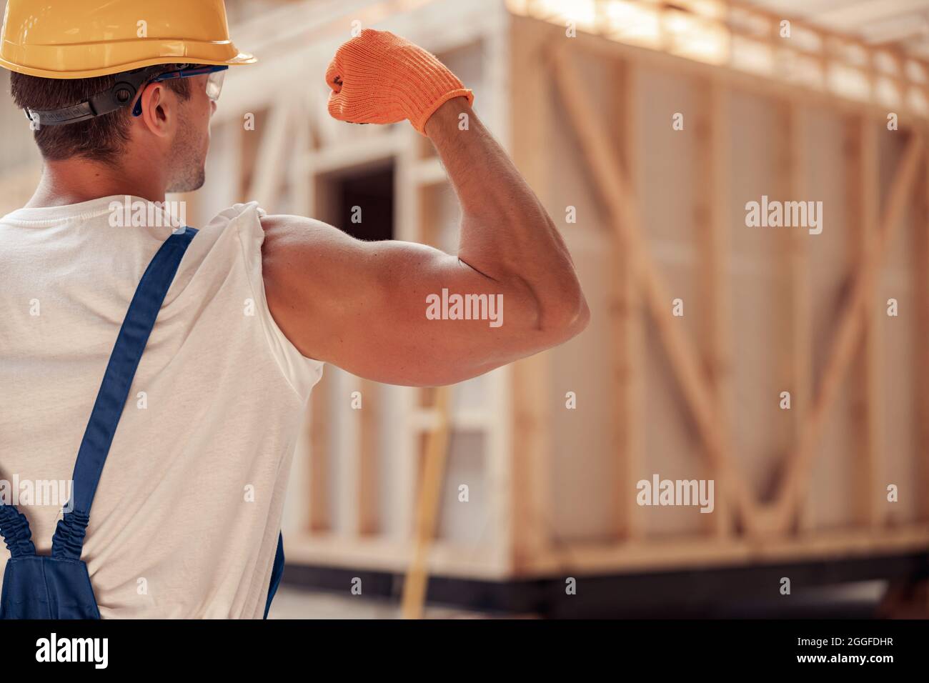 Athletischer junger Mann Baumeister demonstriert seinen muskulösen Arm Stockfoto