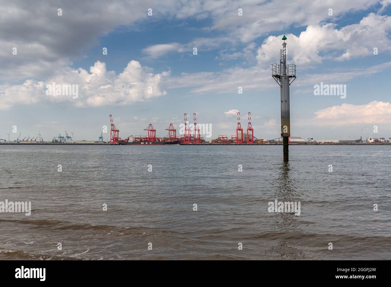 New Brighton, Wirral, Großbritannien: Lateraler Markierungsposten, der den Flusskanalrand an der Mersey-Mündung anzeigt. Kräne von Seaforth dockt in der Ferne an Stockfoto