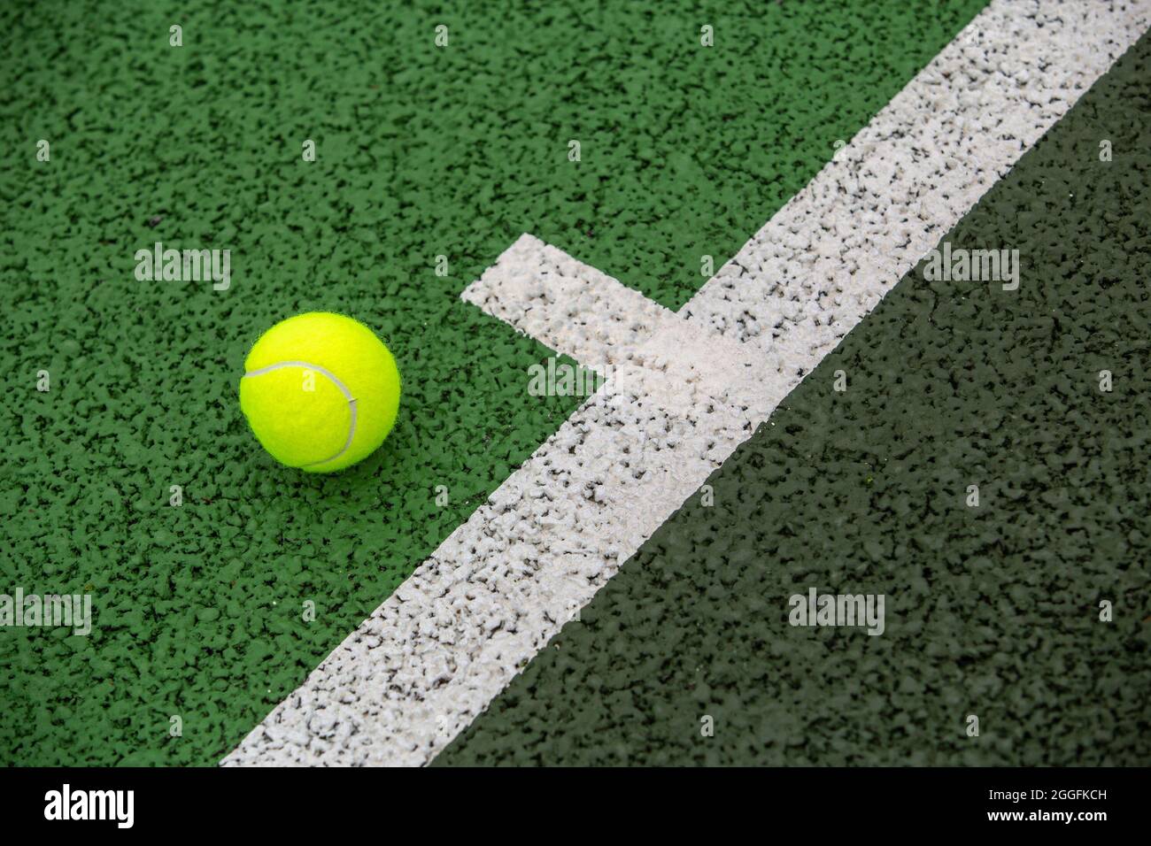 Ein Tennisball an der Grundlinie auf einem grünen Tennisplatz mit harter Oberfläche Stockfoto