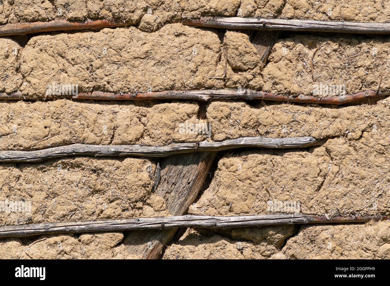 Wand aus Gemisch Schmutz, Schlamm und Weizenspalte, unterstützt mit Holzstäben Stockfoto