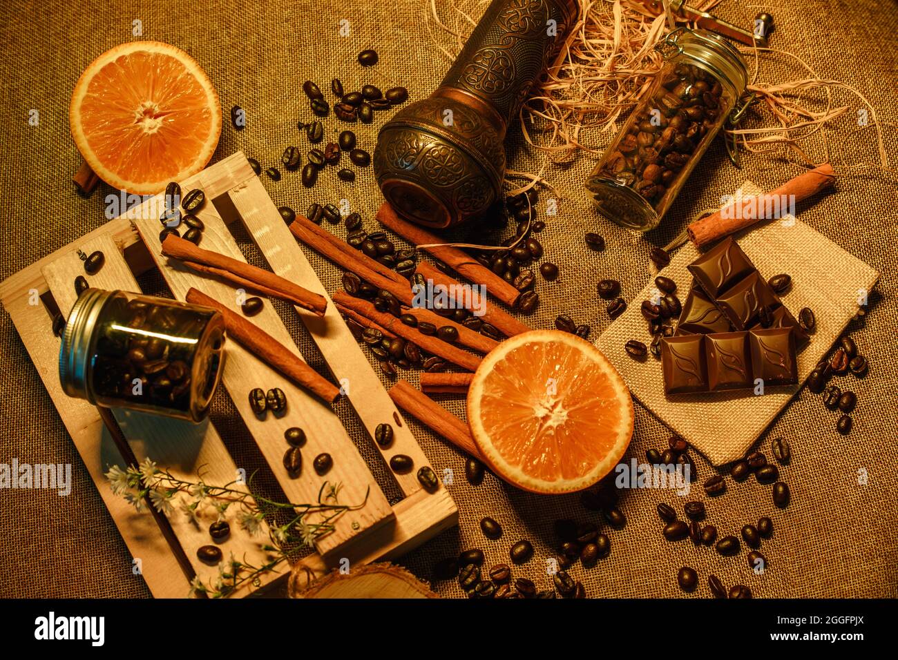 Blick von oben auf Kaffeebohnen mit Orange, Schokolade, Kaffeemühle und Holzkiste. Produktfotografie von Kaffeebohnen Stockfoto